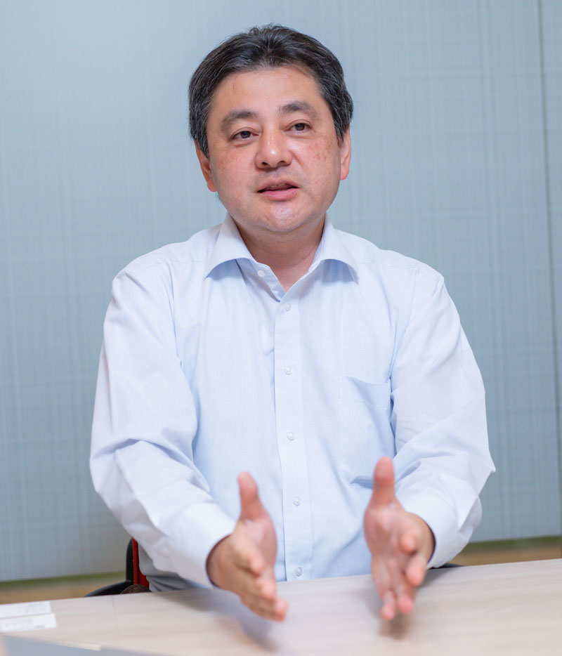 A person wearing a white shirt gesturing with open hands over a desk.