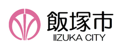 The official logo of Iizuka City, featuring Japanese text "飯塚市" and English text "IIZUKA CITY" with a pink circular emblem.