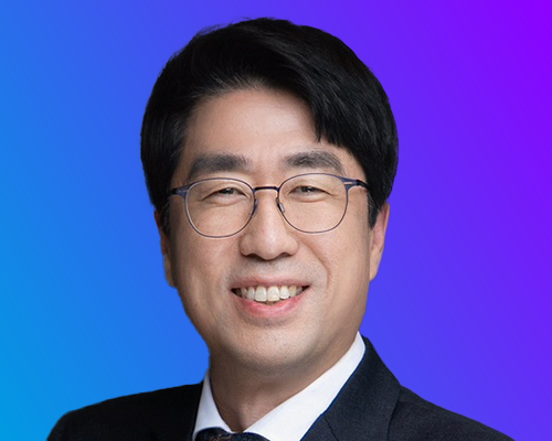 A person in formal attire against a gradient blue-to-purple background.