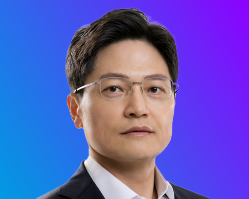 A person wearing a suit and glasses against a gradient blue-to-purple background.