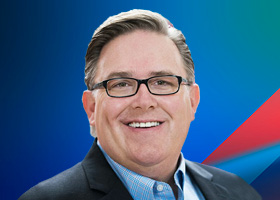 Portrait of smiling man in suit and glasses on blue background