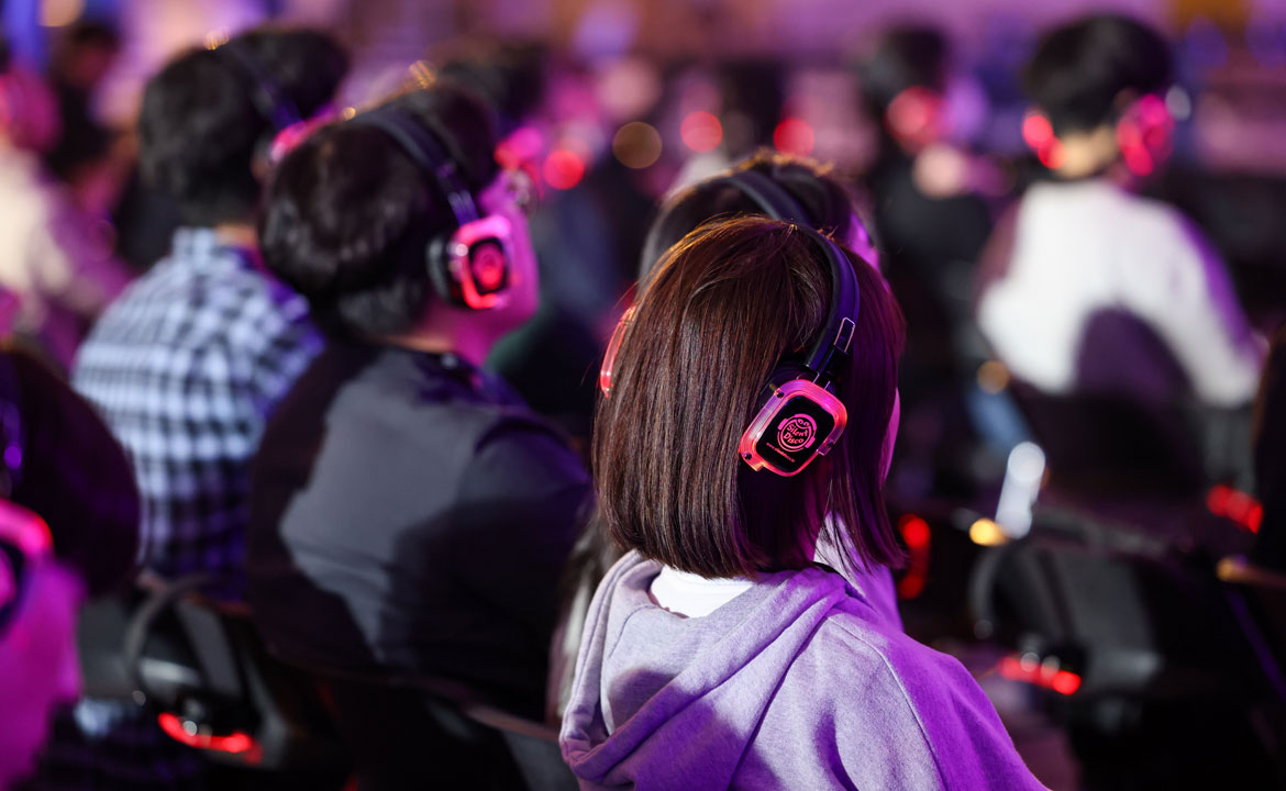 People wearing glowing headphones at a silent event, seated in rows under colorful lighting.