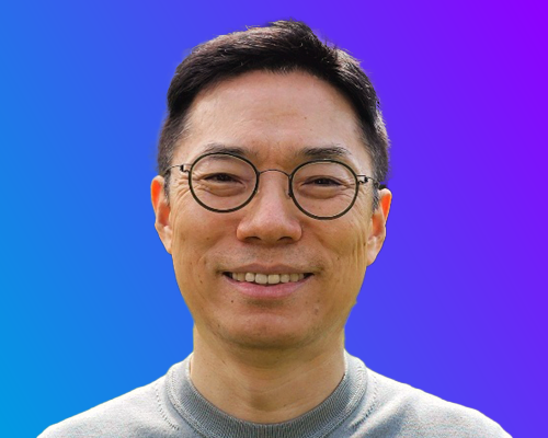 A person wearing a gray sweater against a gradient blue-to-purple background.