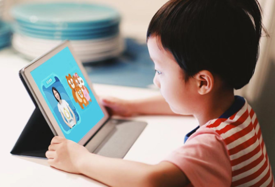 A young child using a tablet to follow an educational Python tutorial with colorful illustrations on the screen.
