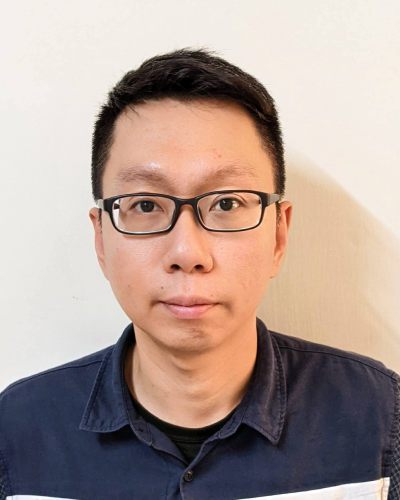 A portrait of a man wearing glasses and a blue shirt, facing the camera against a plain background.