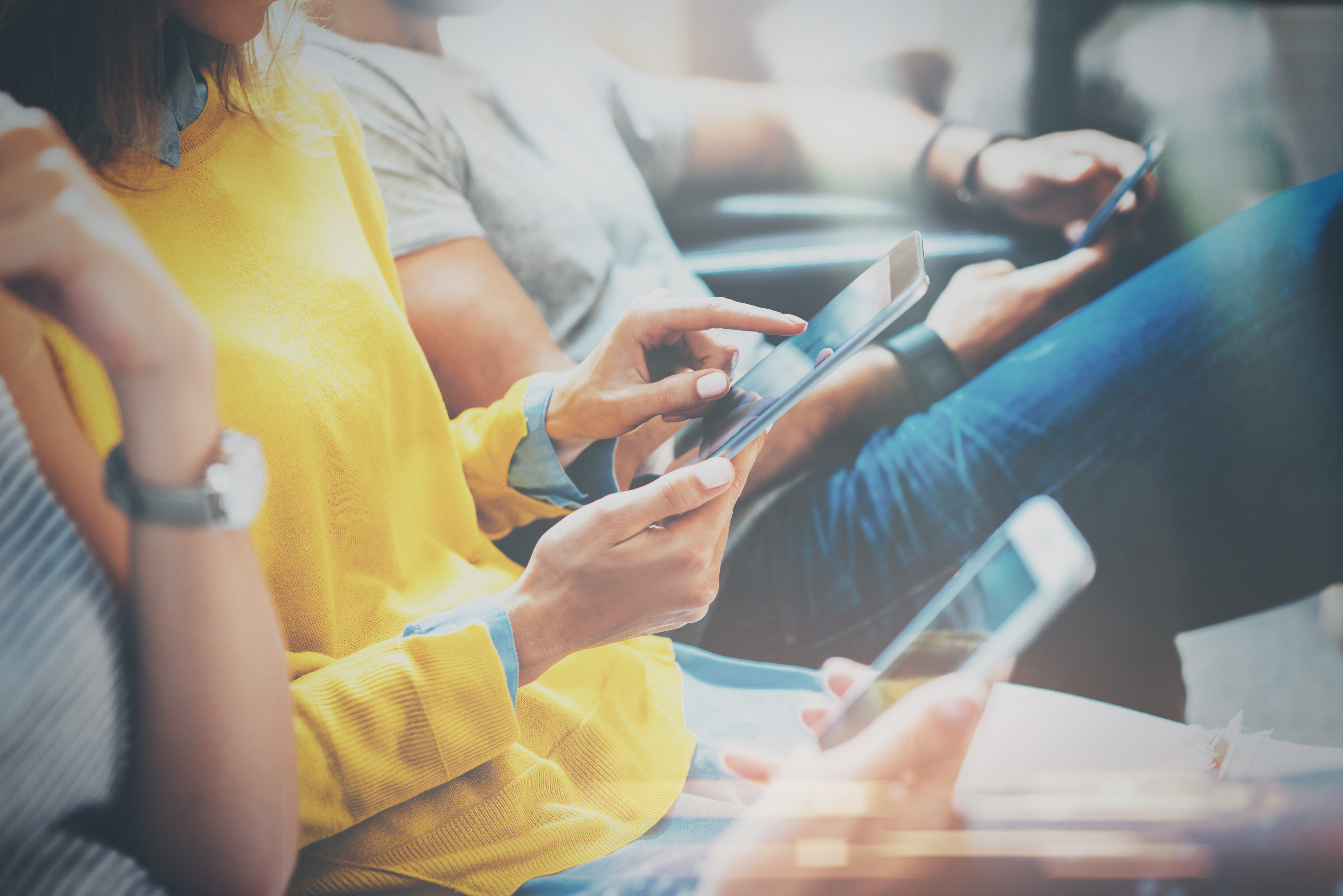 Group of young hipsters sitting on sofa holding en hands and using digital tablet,smartphone.Coworking team concept.Horizontal,blurred background; Shutterstock ID 573110821; PO: TR : COUNTRY EXPANSION GATEWAY LAUNCH ID#1117797; Job: Country Expansion; Client: Gateway; Other: TR