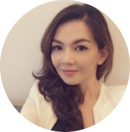 A person with long, wavy brown hair wearing a white top over a black shirt.