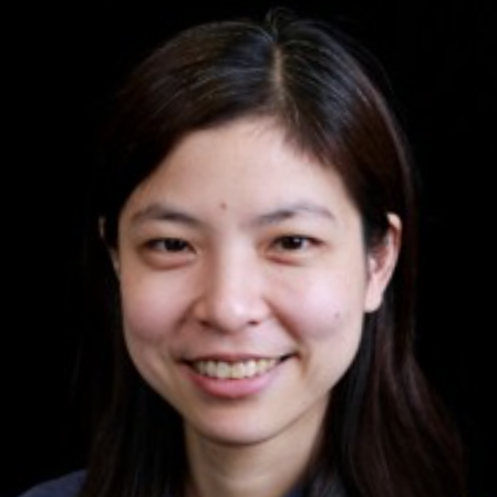 A portrait of a woman with straight dark hair, smiling and facing the camera against a black background.