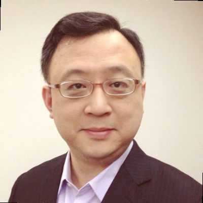 A professional headshot of a male wearing glasses and a suit, posed against a plain background.