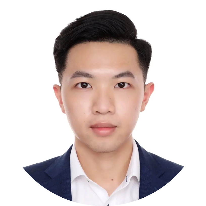 A person wearing a white collared shirt and navy blazer, with neatly styled black hair.