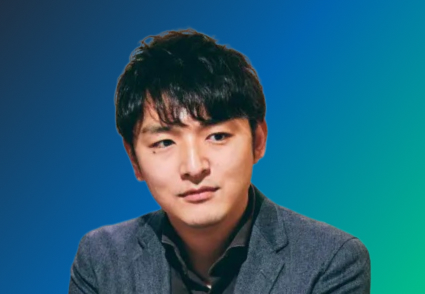 A person wearing a gray blazer against a gradient blue-green background.