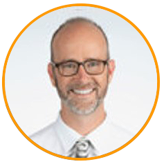 A professional headshot of a smiling person wearing glasses, a white shirt, and a tie, with a beard and a bald head, framed within an orange circle.