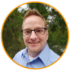 A person wearing a light blue collared shirt, standing outdoors with trees in the background, framed by an orange circle.