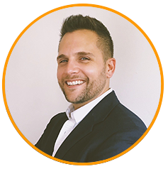 Professional headshot of a smiling man in business attire, facing slightly to the side, with a neutral background and orange circular border.