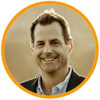 Portrait of a smiling man with short hair wearing a suit, set within a circular orange border.