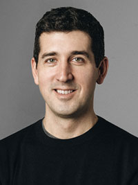 A professional headshot portrait of a man in a black shirt against a neutral gray background, taken for the 2024 Seller Conference.