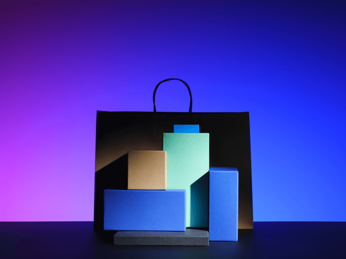 A black shopping bag surrounded by colorful boxes, displayed against a purple and blue gradient background.