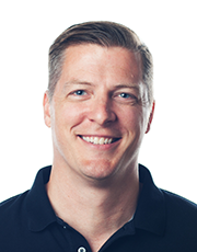 Portrait of a smiling man wearing a dark shirt, photographed against a white background.