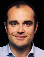Portrait of a man with a light blue shirt against a black background