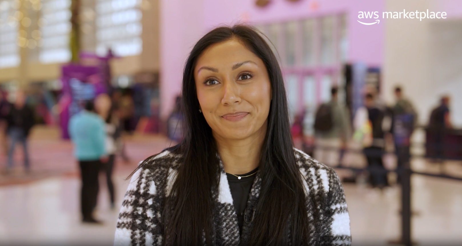 Media and entertainment professional smiling at indoor AWS event showcasing AWS media solutions with AWS Marketplace logo