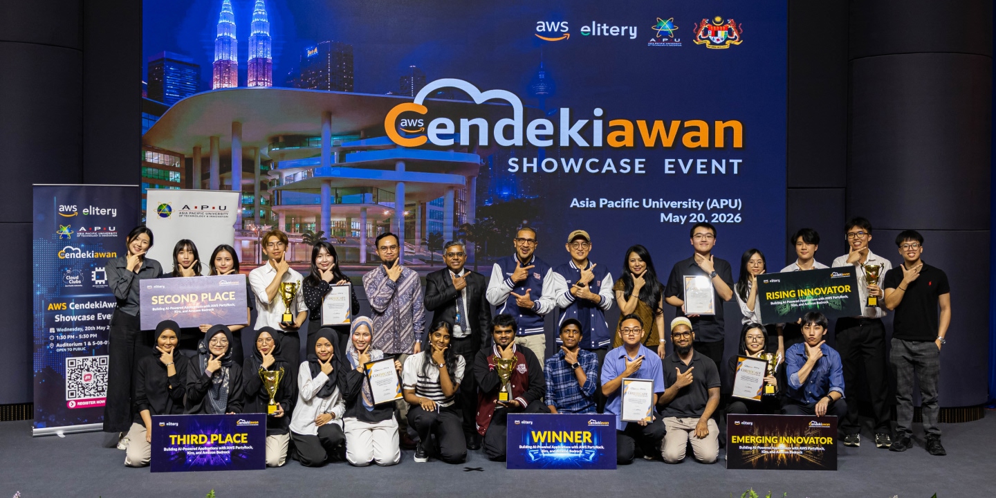 Group of people posing with their certificates and trophies in front of a stage.