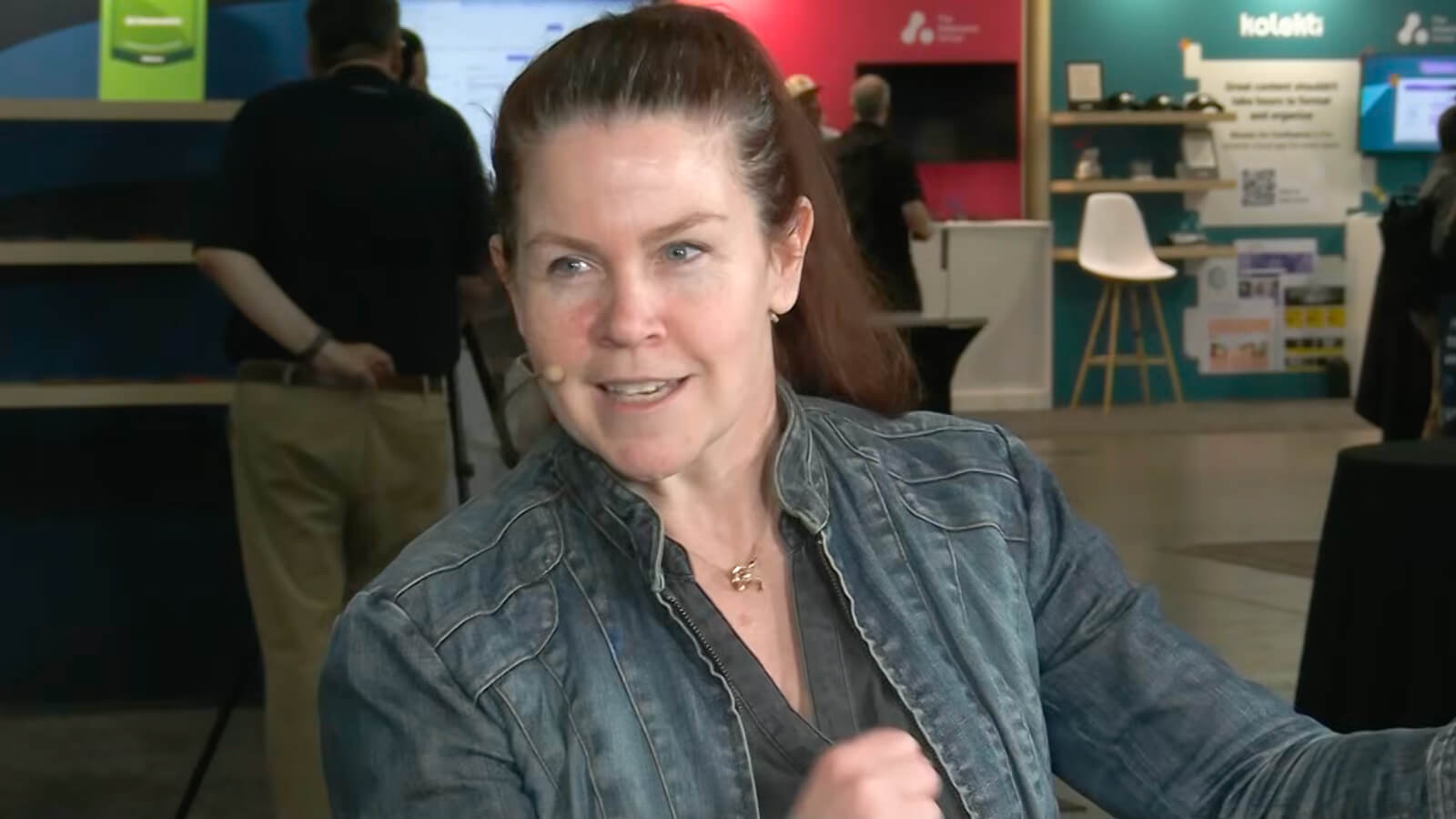 Woman wearing a headset microphone speaking during an interview at an event space