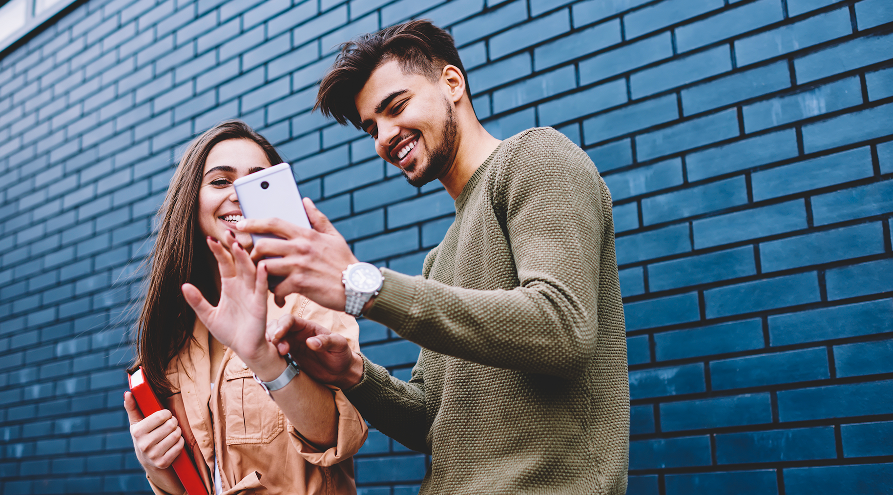 Man and woman smiling while looking at a smart phone