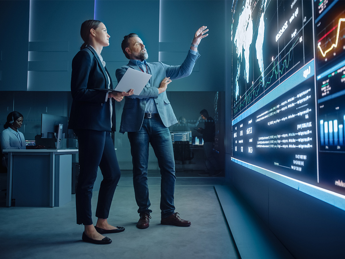 Two people looking at large screens