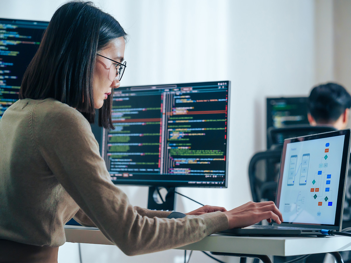 Person working at a desk with multiple screens