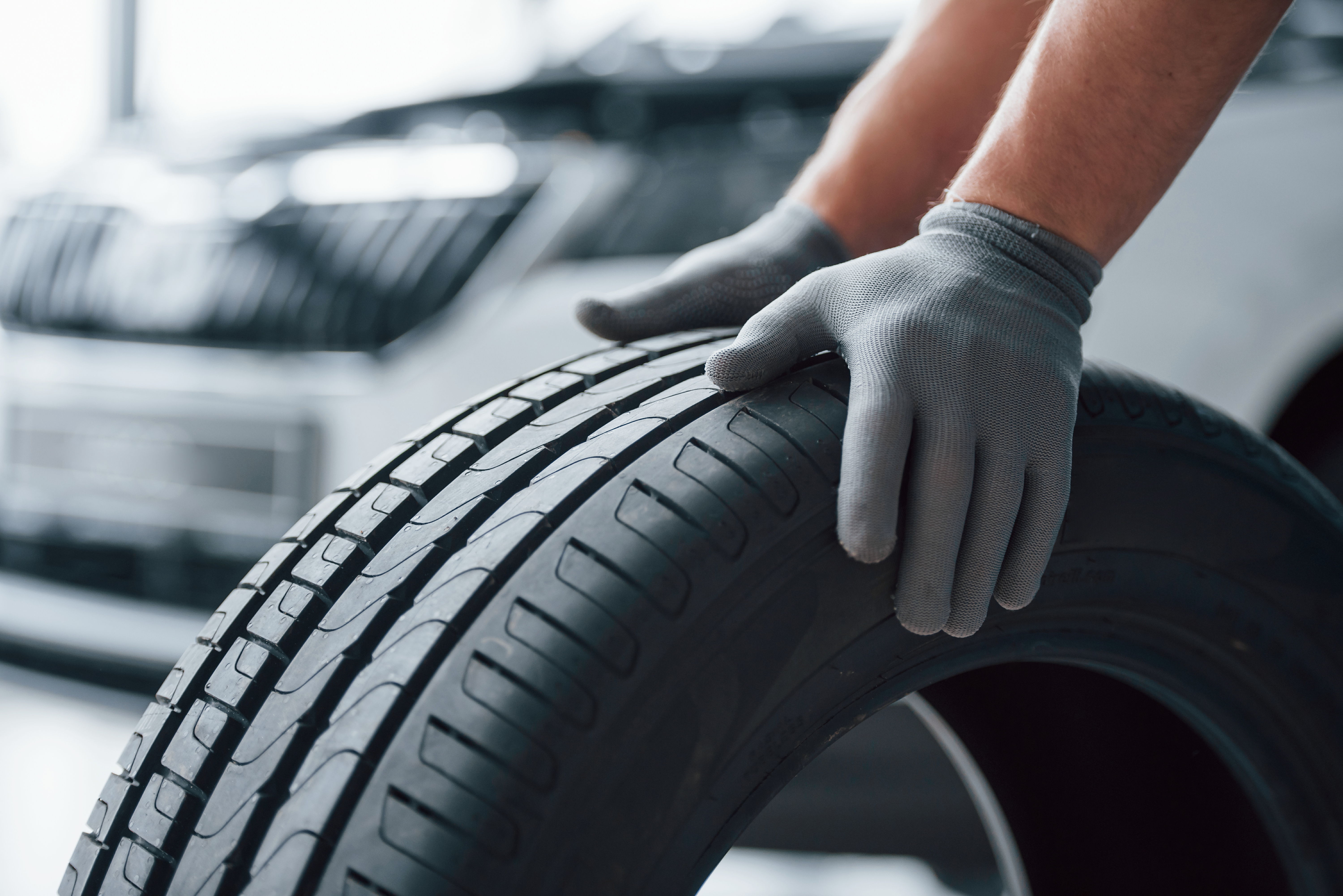Hands only. Mechanic holding a tire at the repair garage. Replacement of winter and summer tires Hands only. Mechanic holding a tire at the repair garage. Replacement of winter and summer tires