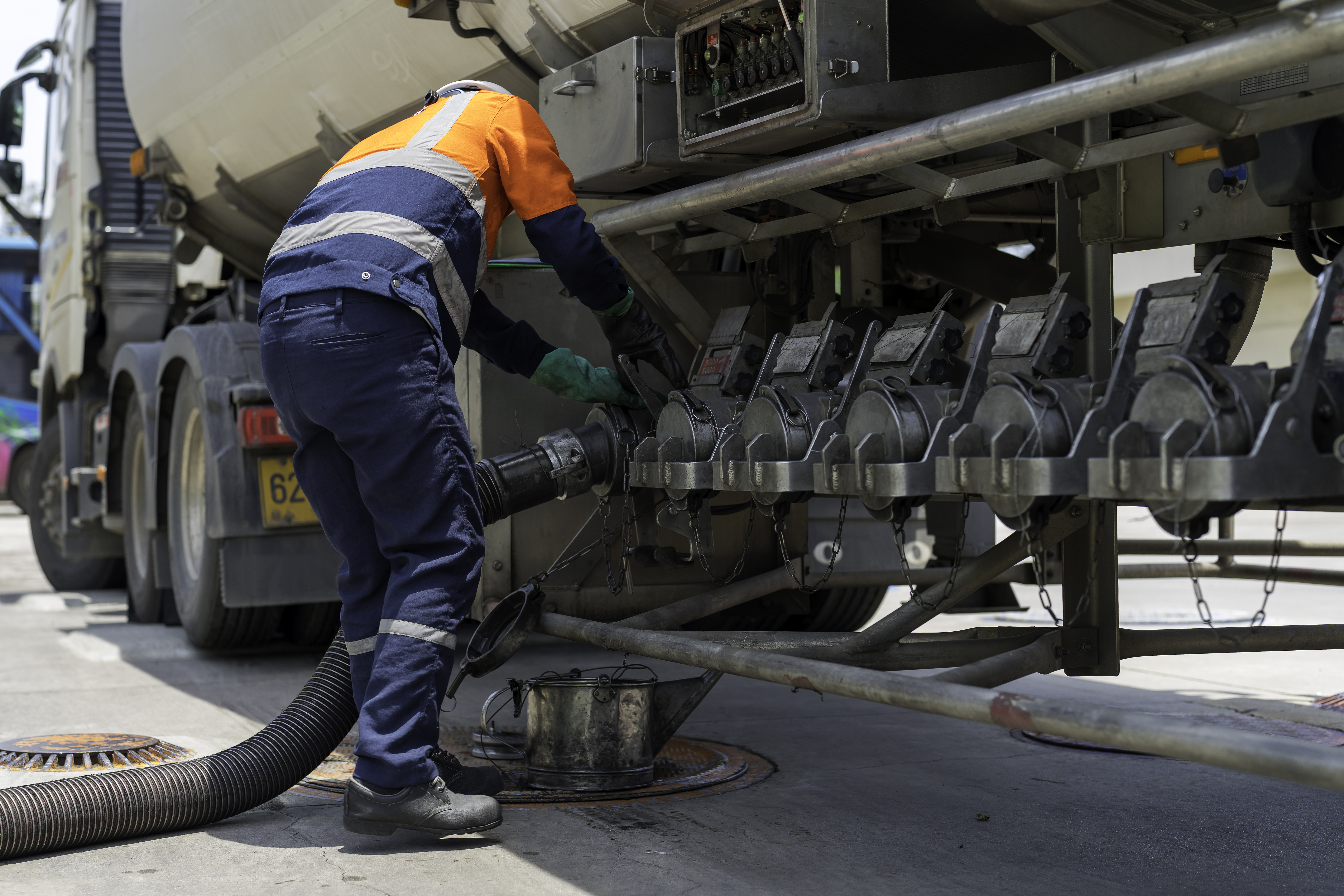 A tanker truck driver delivers gasoline to a gas station