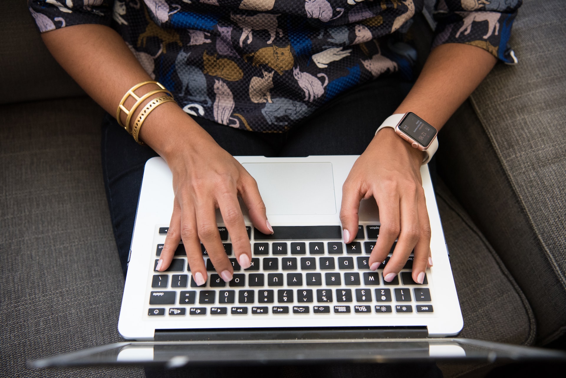 Woman typing on laptop sitting on a couch.