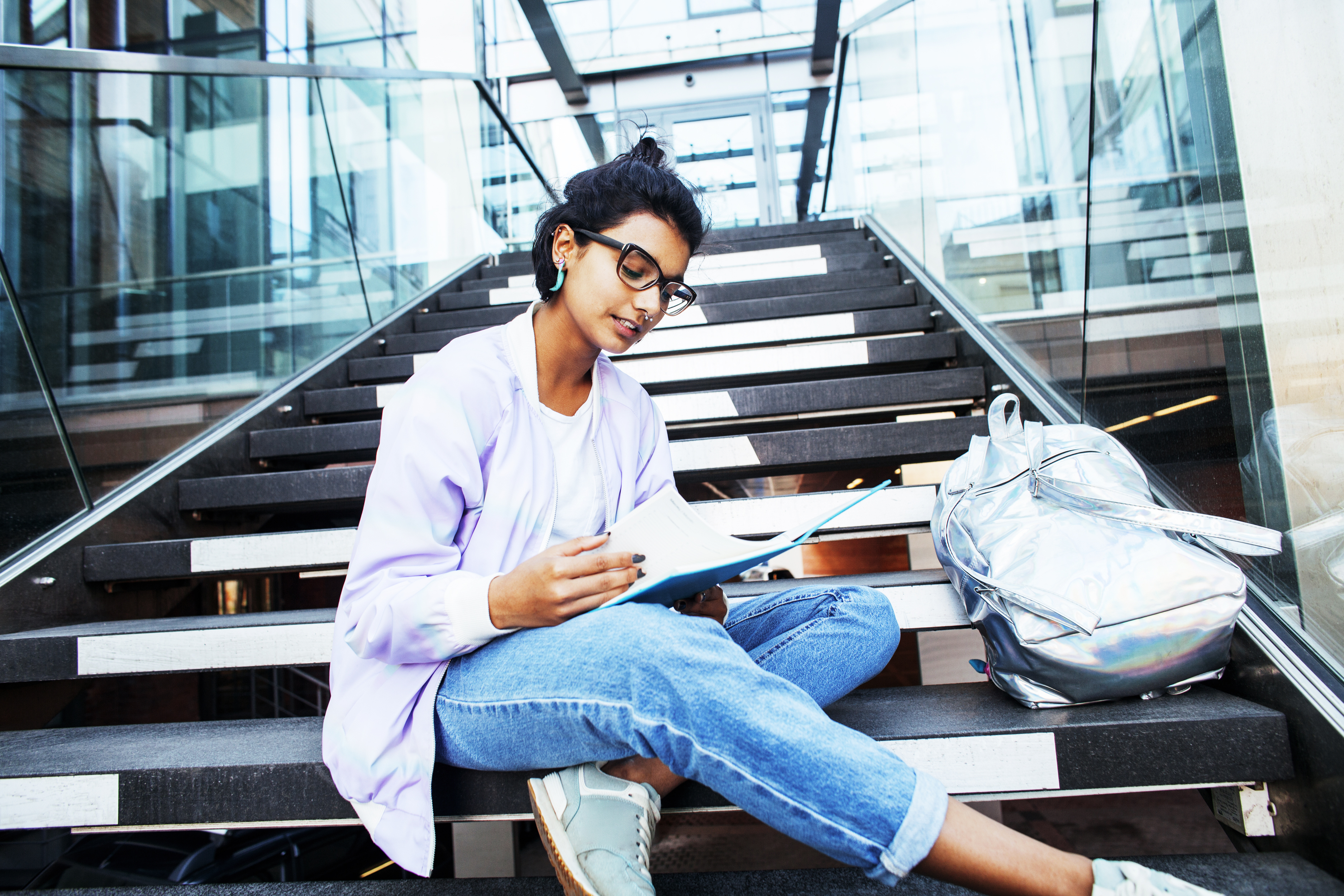 A woman sits on steps studying.