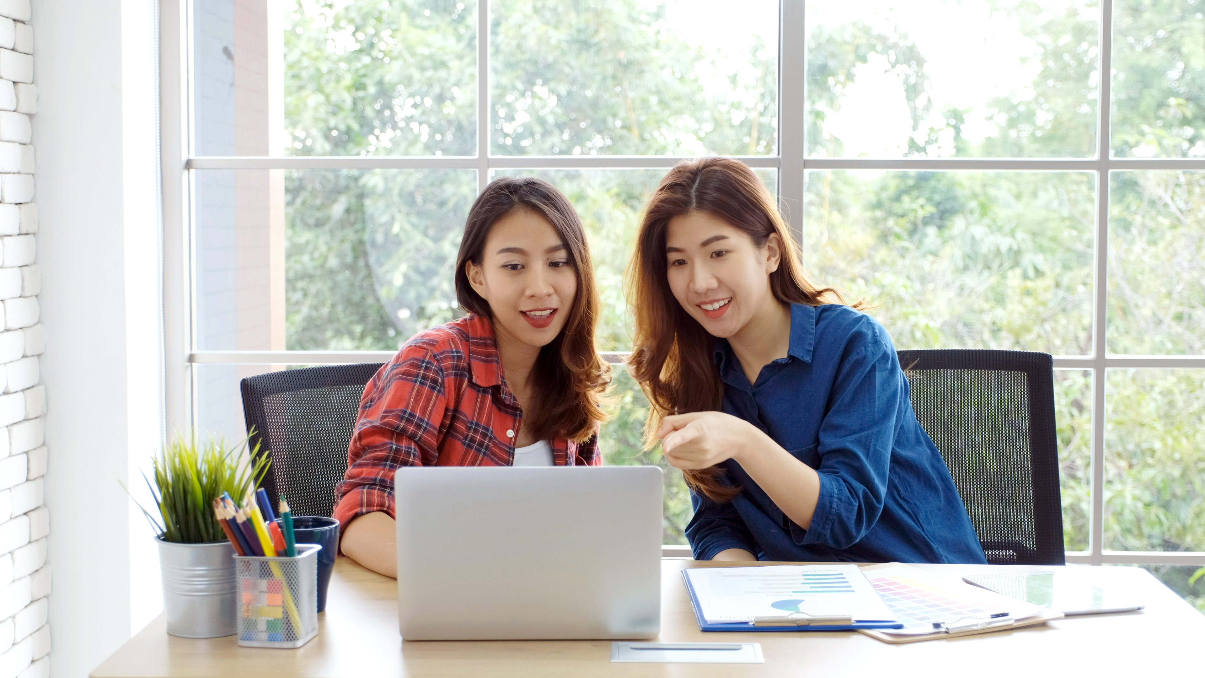 Two women look at a computer and discuss 