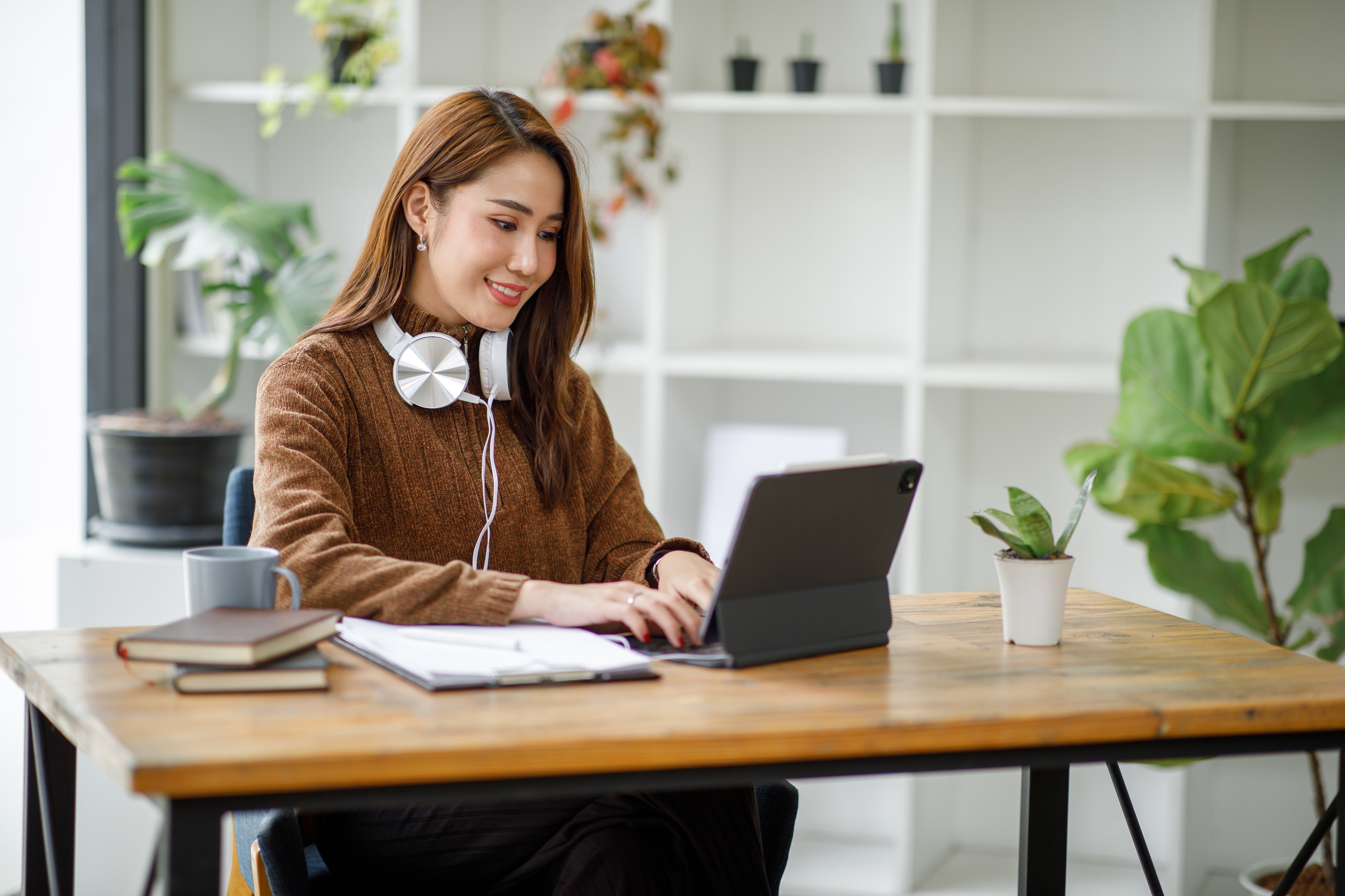 A woman sitting at her desk and smiling at her open laptop screen.