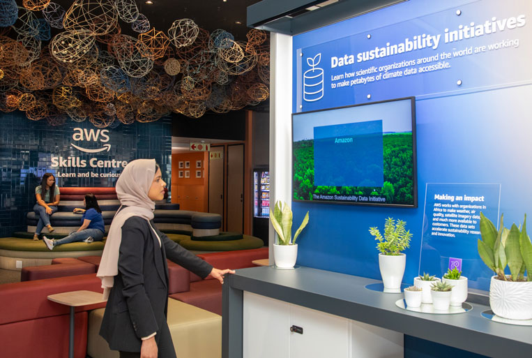 A woman wearing a hijab standing in from of the Cloud Discovery exhibit at the AWS Skills Ceter Cape Town