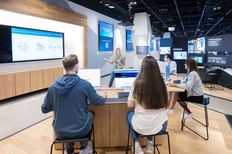 Four students sit at a desk listening to an instructor inside of an AWS Skills Center