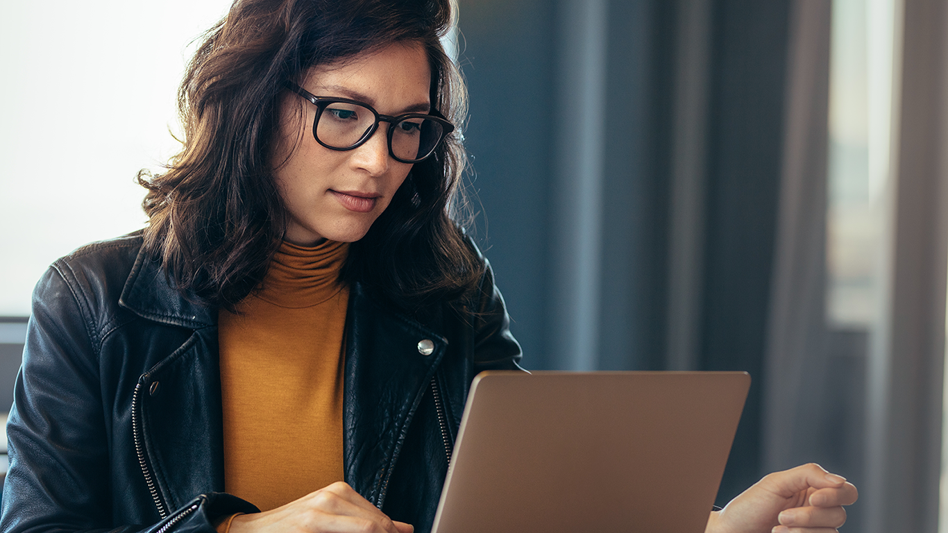 A woman wearing eyeglasses is sitting at a desk with a laptop and learning how to run security applications in the AWS Cloud. A woman wearing eyeglasses is sitting at a desk with a laptop and learning how to run security applications in the AWS Cloud.