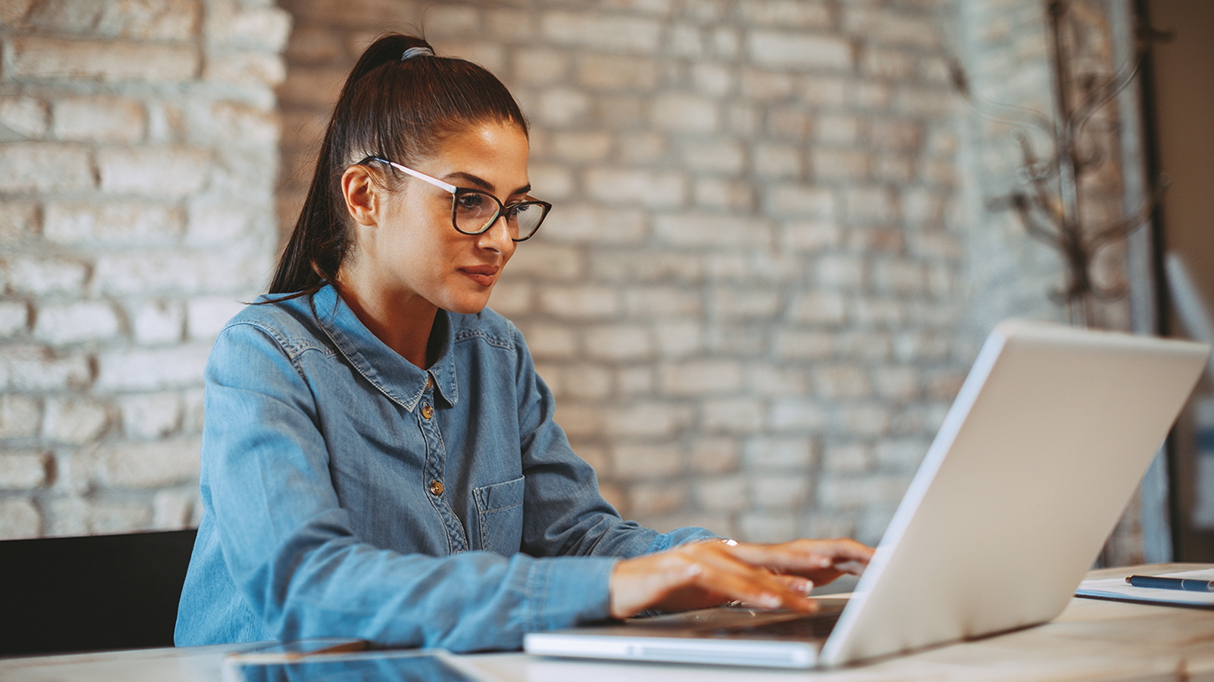 A woman wearing eyeglasses is sitting with a laptop and learning about AWS storage services