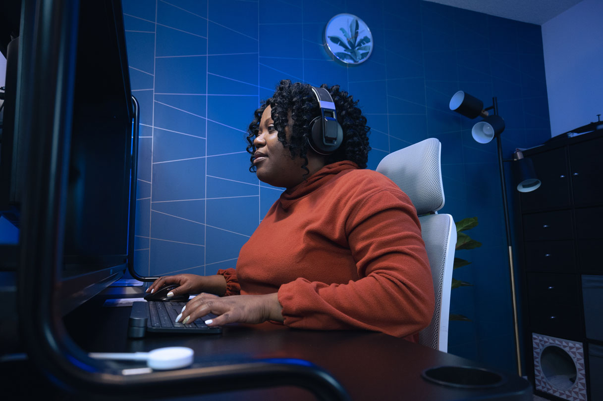 Mulher negra com fones de ouvido fazendo um curso dos Laboratórios Builder da AWS em seu desktop