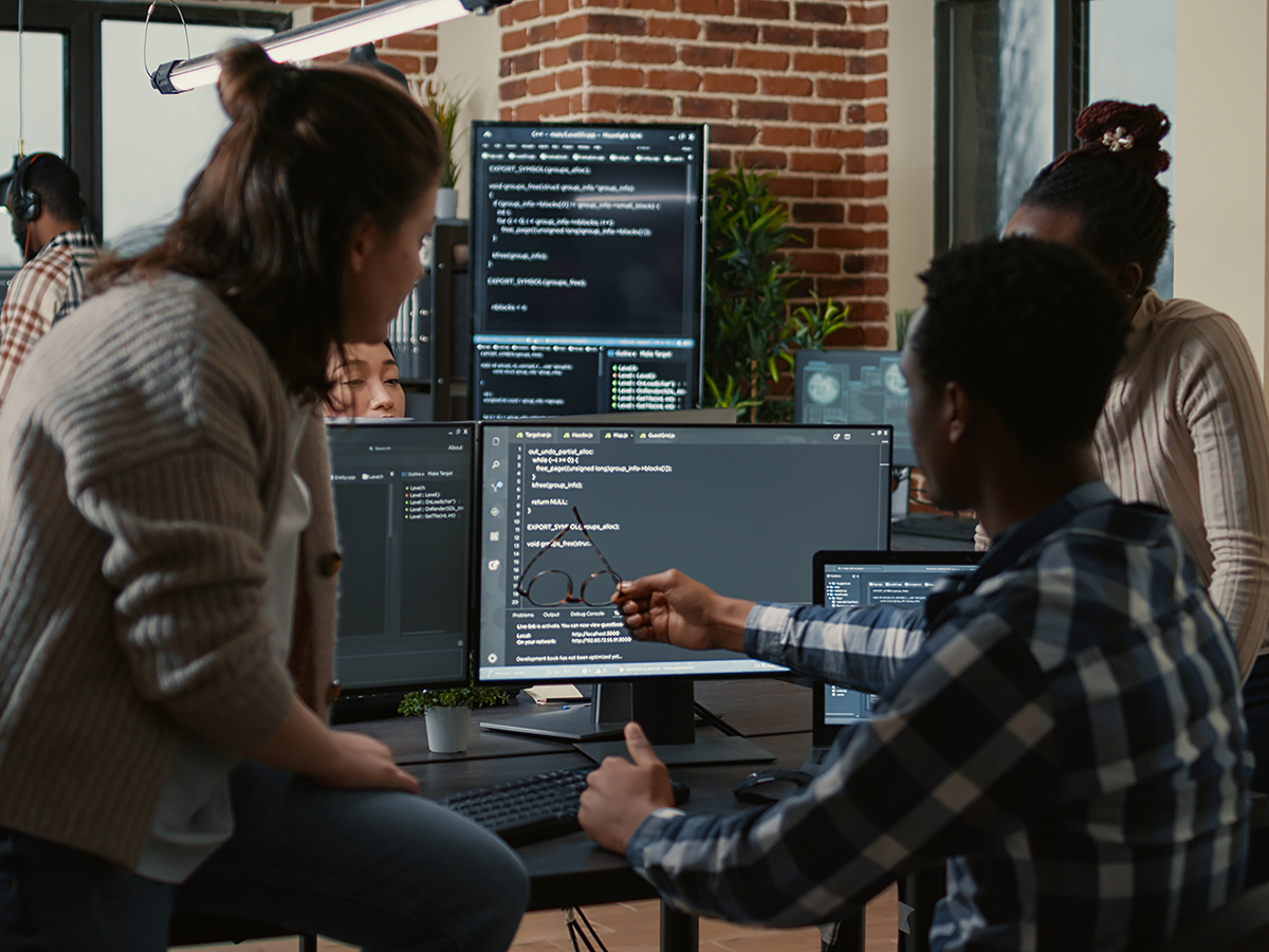 Programer sitting on desk discussing with mixed team of software developers about artificial intelligence